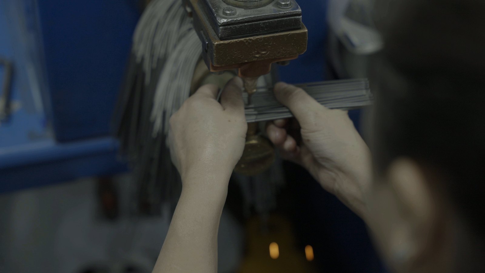 Operator preparing terminal pins in a fixture before they are welded to the coil