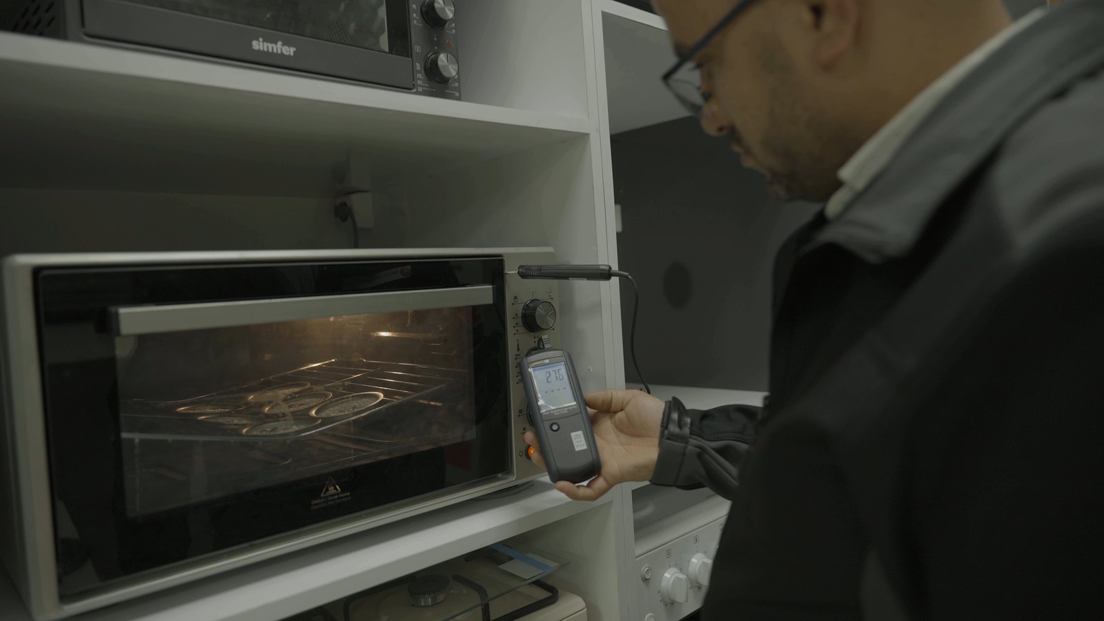 Engineer measuring an oven heating element on a test bench