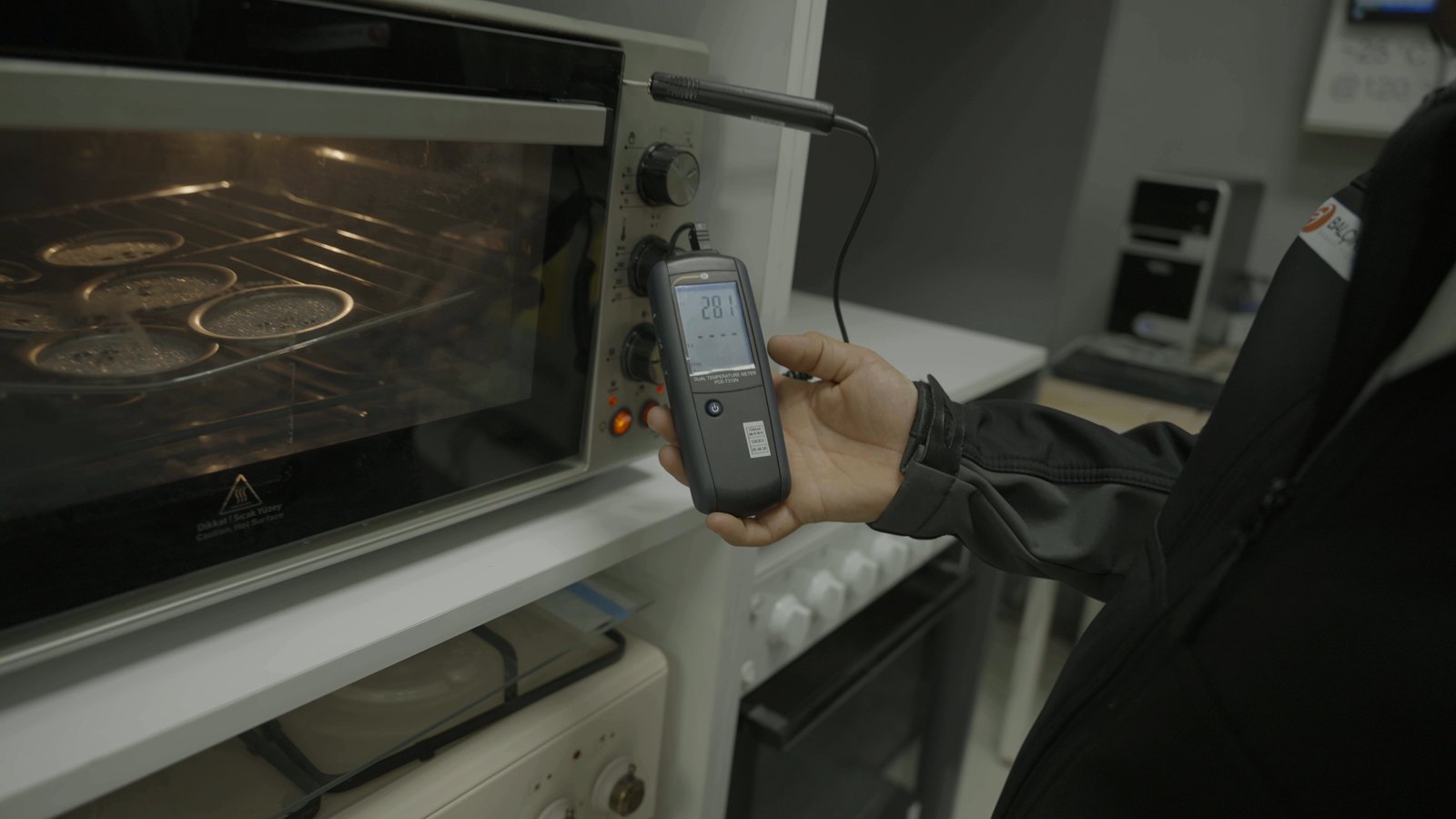 Laboratory technician measuring temperature and power of an oven on a test bench